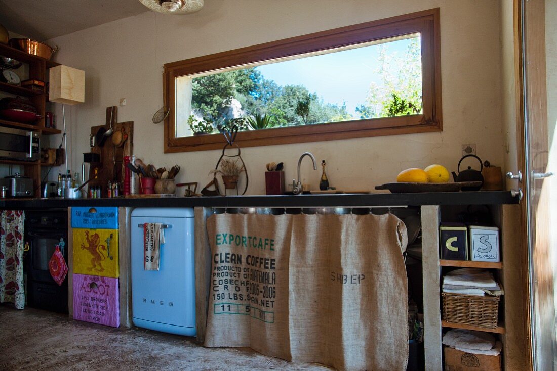 Quirky kitchen counter with coffee-sack curtains and hand-made doors