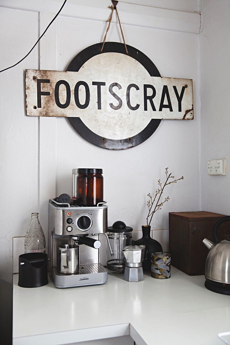 Vintage train station sign above various coffee machines on kitchen counter