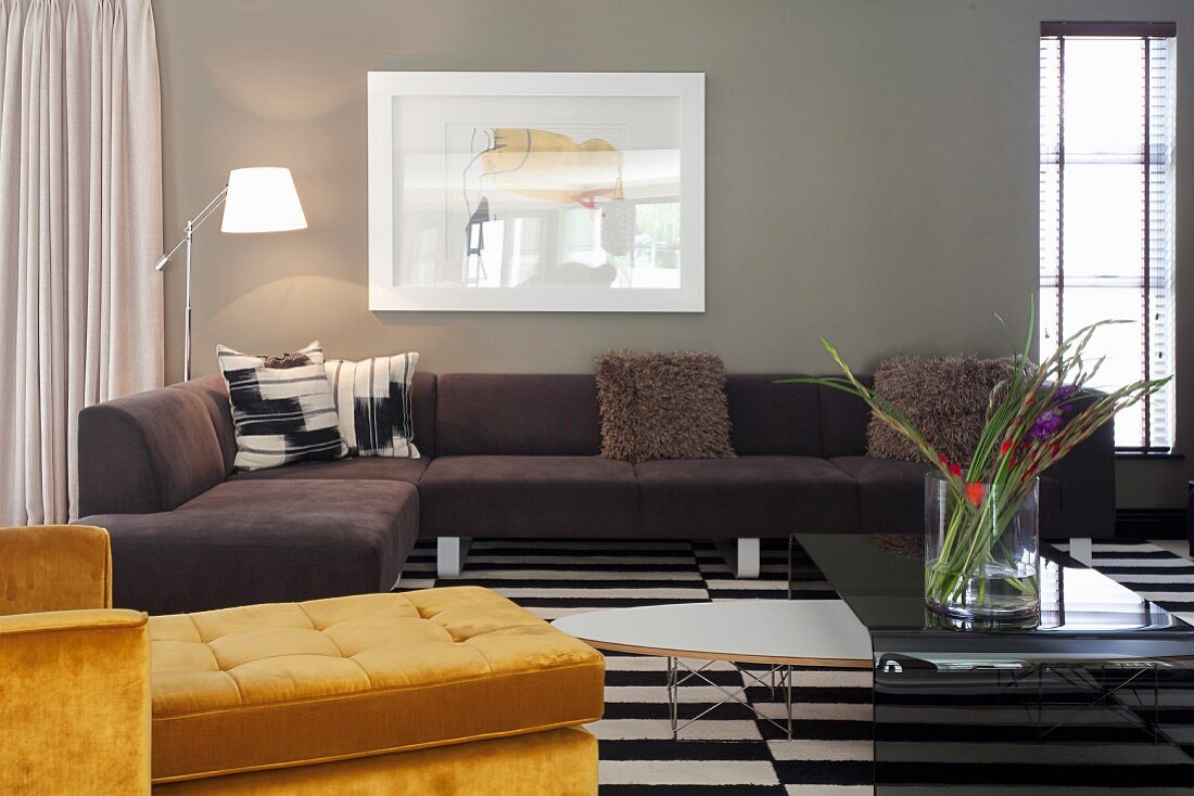 Yellow chaise longue and dark corner sofa around coffee table