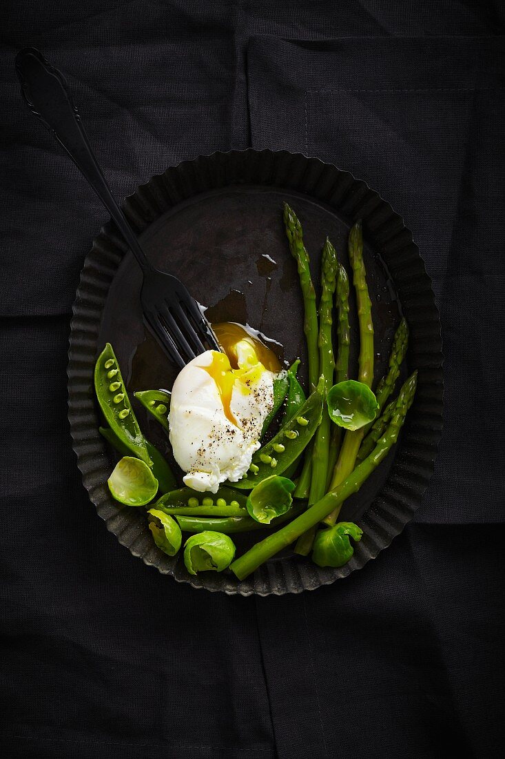 A poached egg on green vegetables (seen from above)