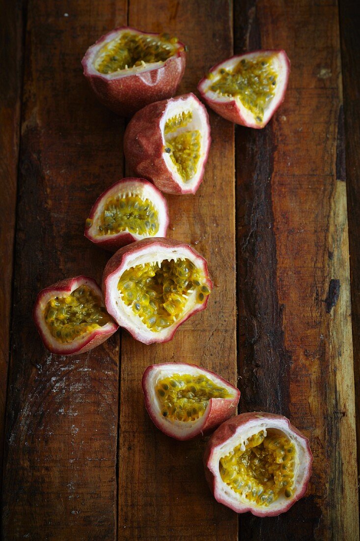 Halved passion fruits on a wooden surface (seen from above)