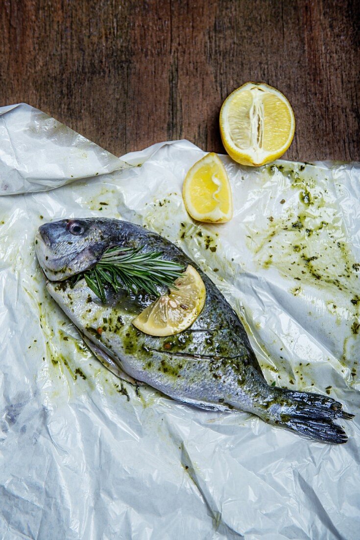 Marinated gilthead with a sprig of rosemary and lemons