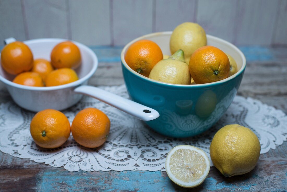 Zitronen und Orangen in blauer Porzellanschüssel, weisses Emaillesieb mit Orangen