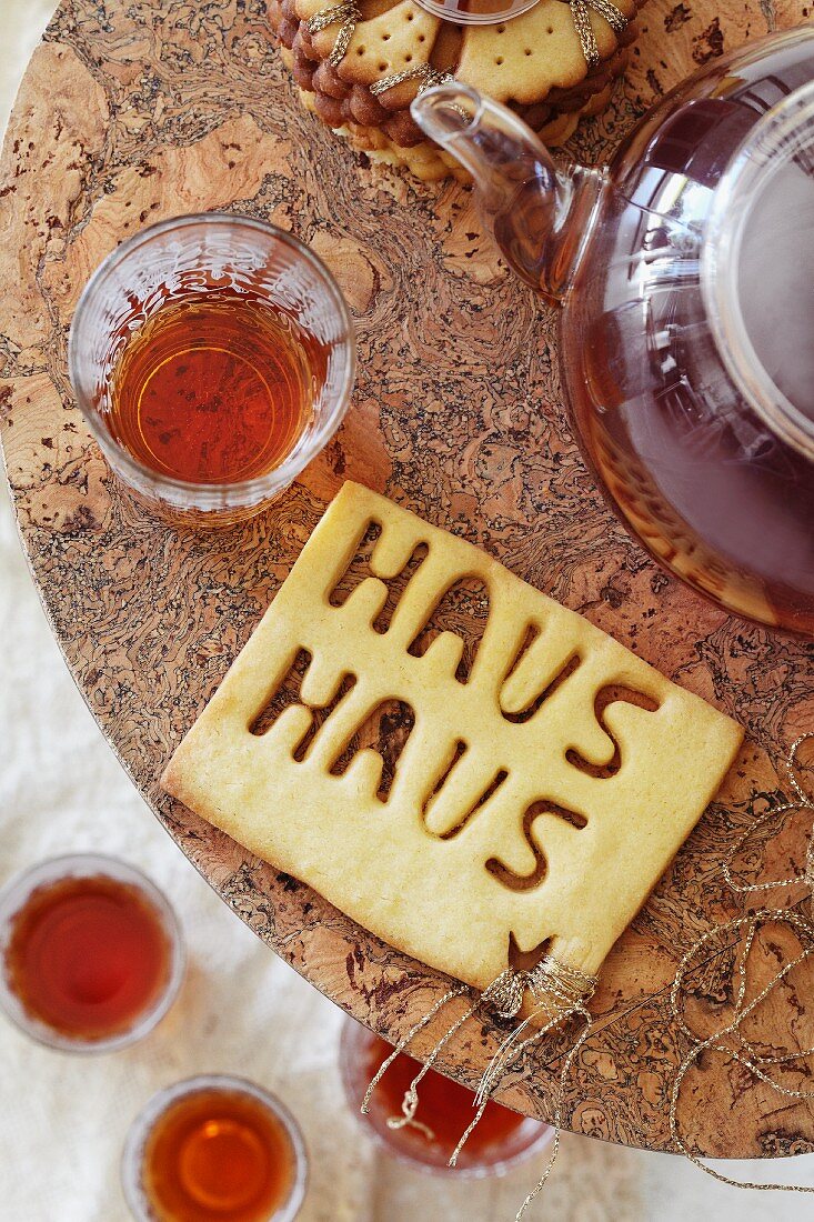 Teatime with the teapots, glasses of tea and biscuits with the word 'Haus'