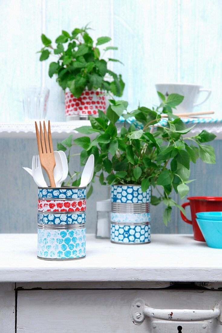 Decorated tin cans holding kitchen utensils and herbs