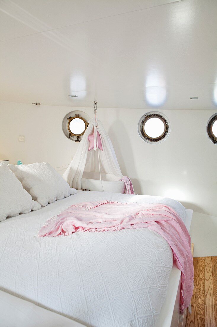 Double bed and cot below portholes in wall