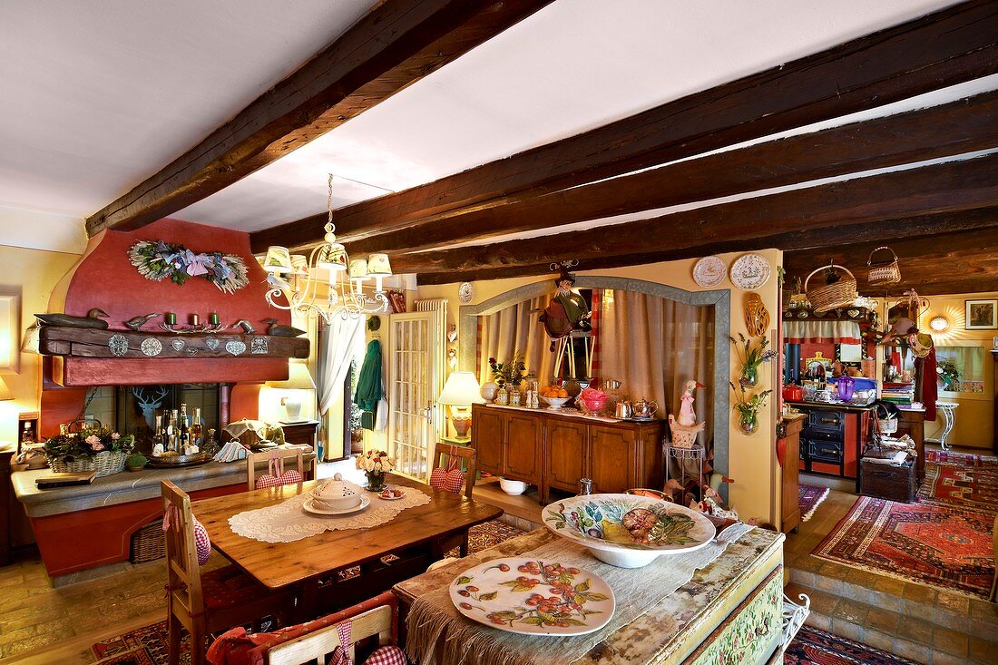 Low, wood-beamed ceiling, dining area and disused fireplace in open-plan interior