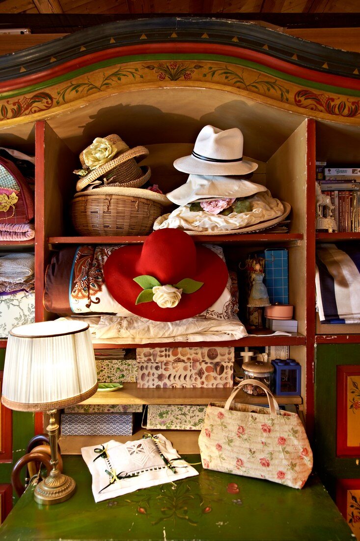Romantic hats and decorative boxes in old, farmhouse cupboard