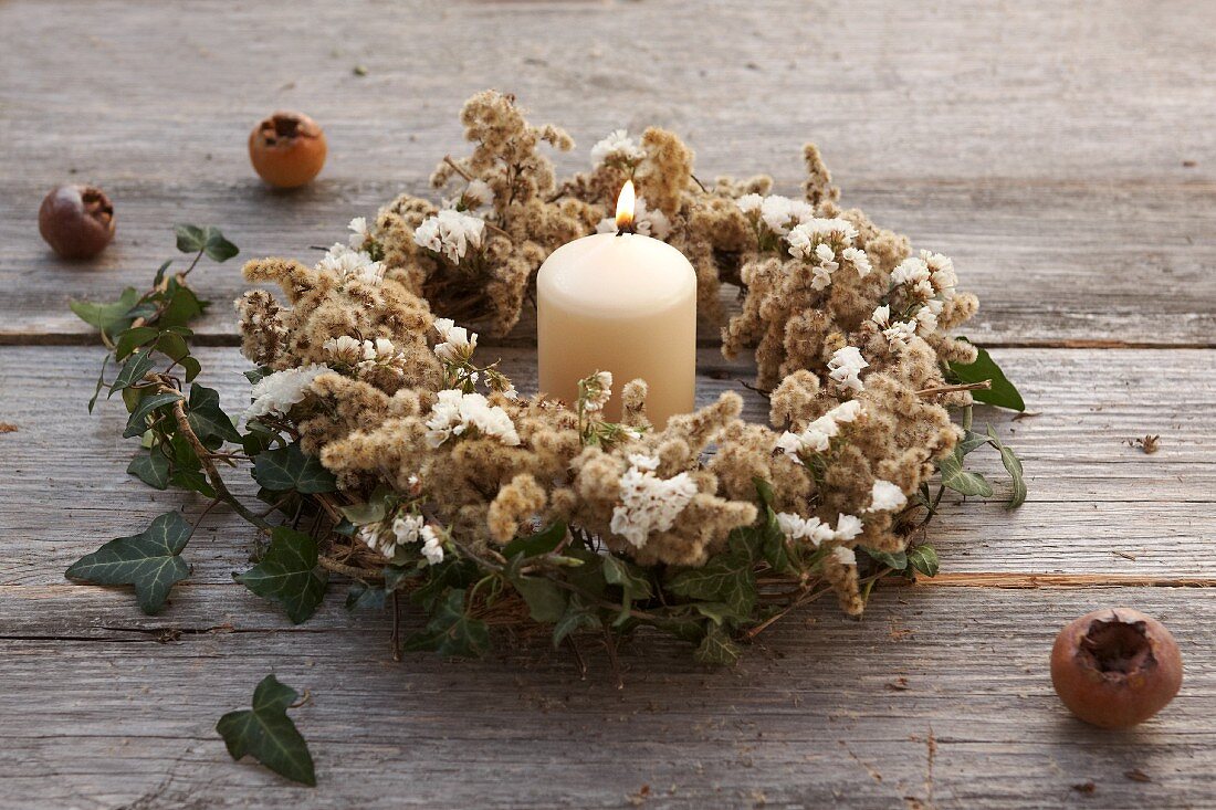 Autumn wreath of dried goldenrod, sea lavender and ivy around candle