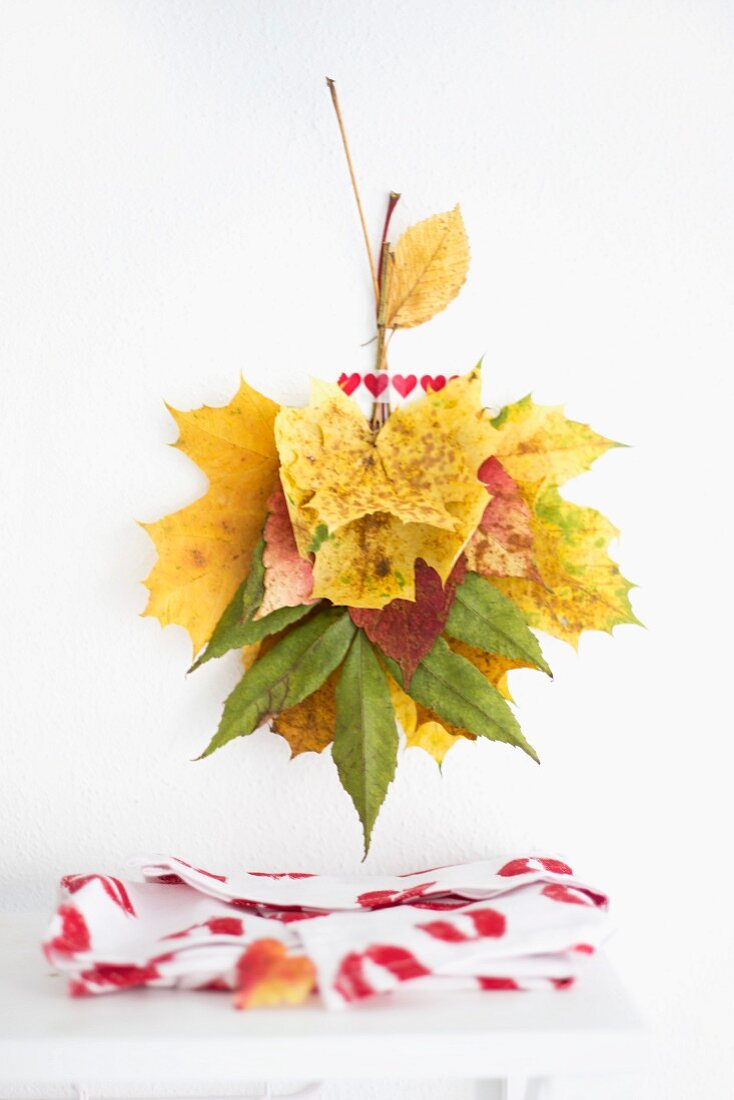 Wall decoration made from autumn leaves and washi table above fabric with pattern of lipstick kisses