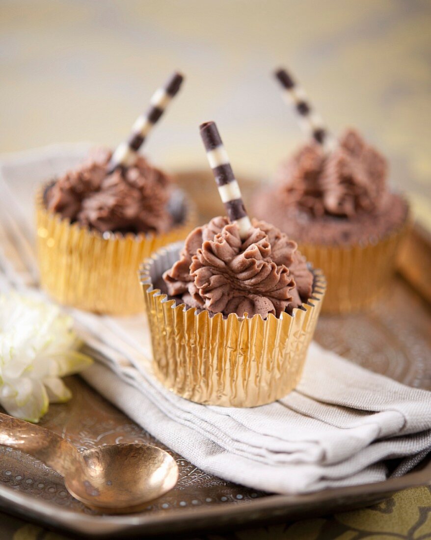 Schokoladencupcakes mit gestreiften Schokoladenröllchen