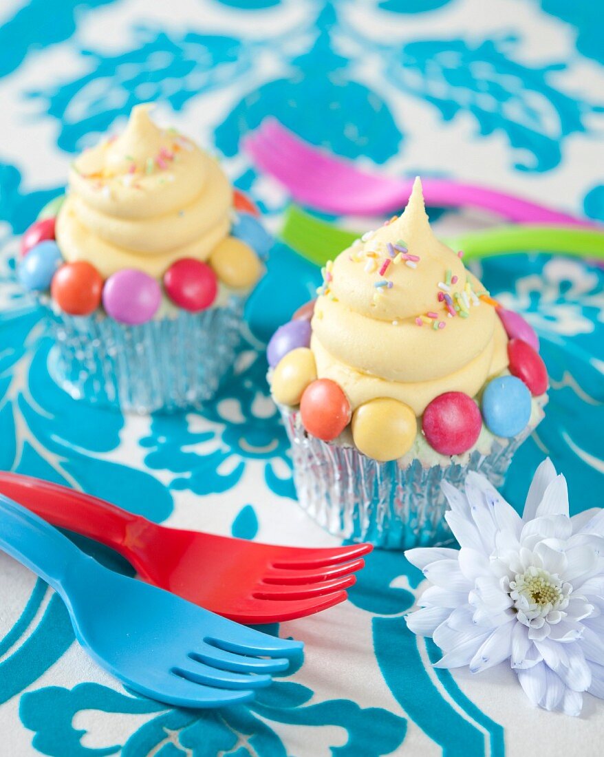 Cupcakes mit bunten Schokolinsen und Zuckerstreuseln