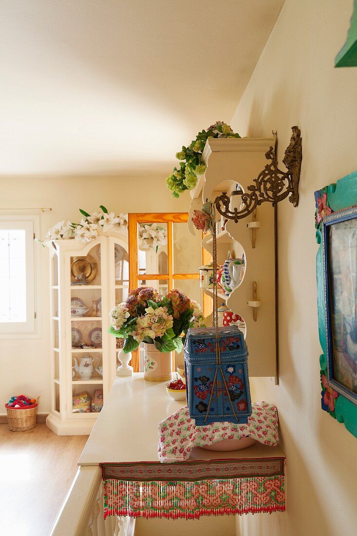 Head of staircase covered with shelf and flower arrangements on romantic plate rack and display cabinet