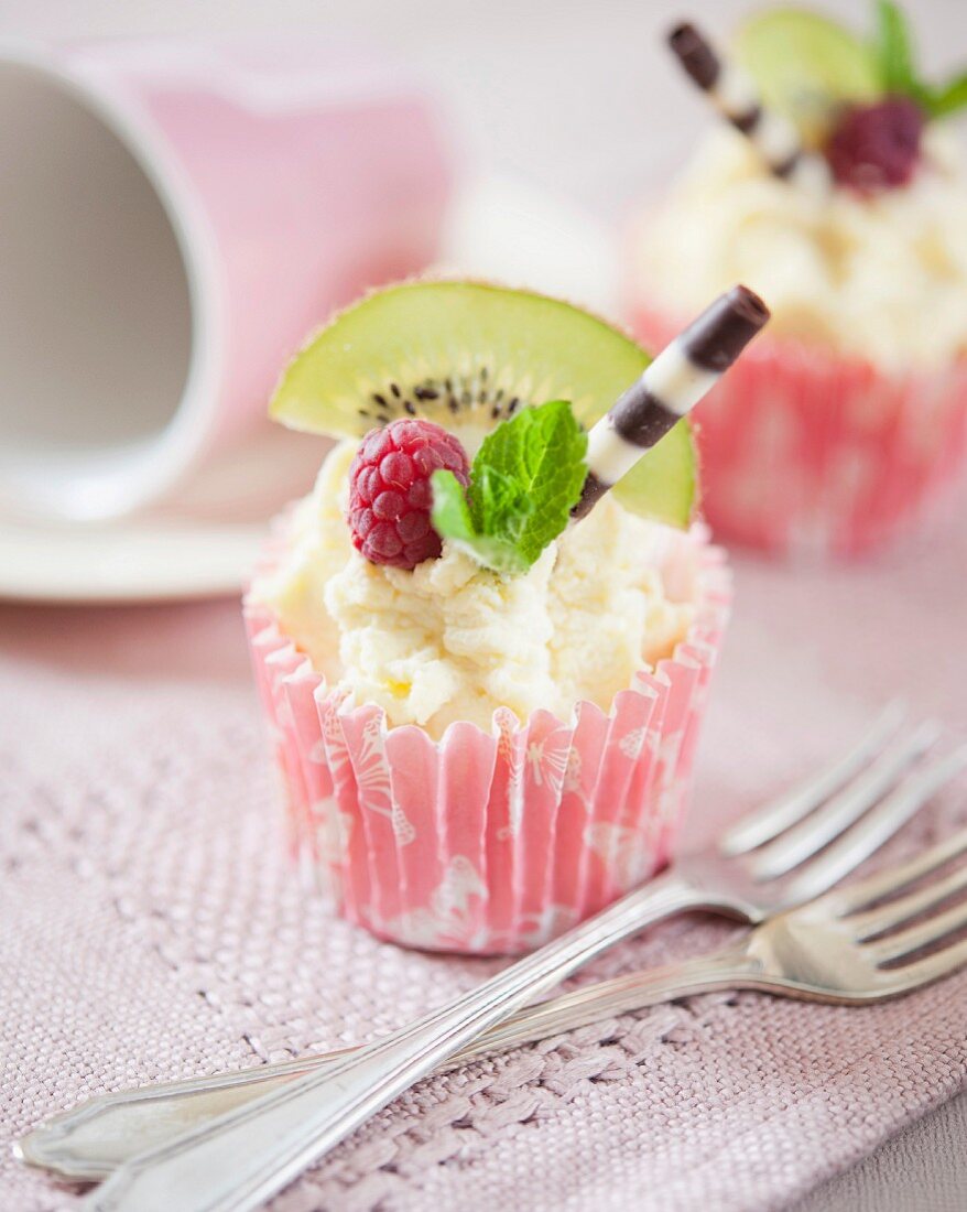 Cupcakes mit weisser Schokoladencreme, Kiwi, Himbeere und Schokoladenzigarre