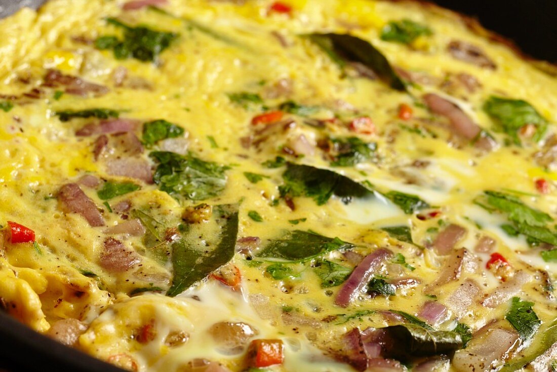 A masala omlette being fried in a pan (close-up)