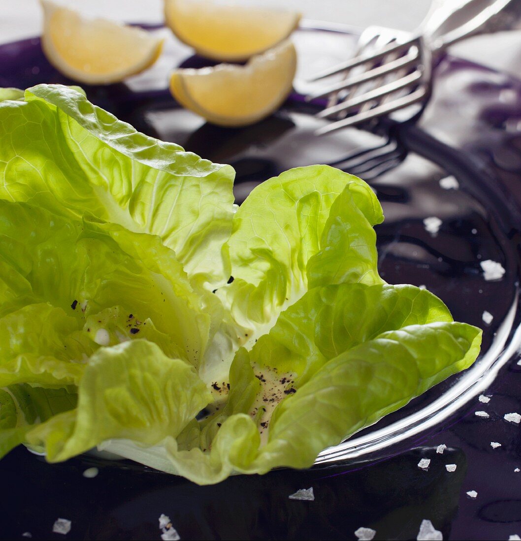 Lettuce leaves with a creamy dressing, salt, pepper and lemons