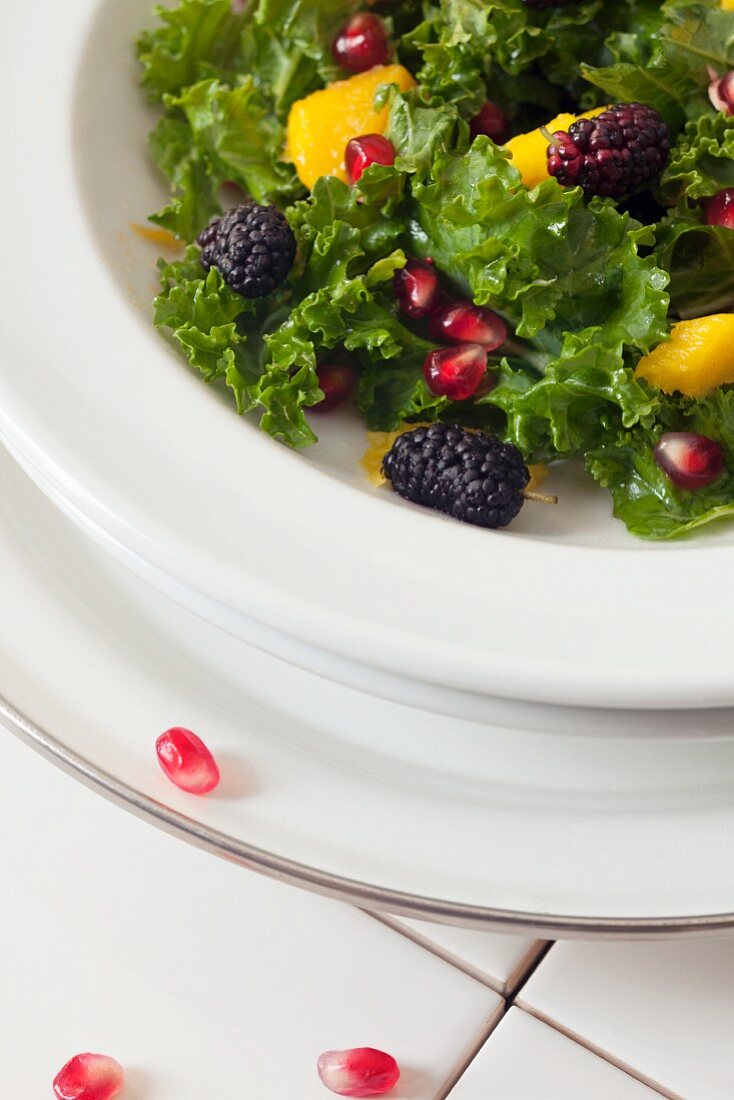 Green kale salad with mulberries, pomegranate seeds and mango dressing