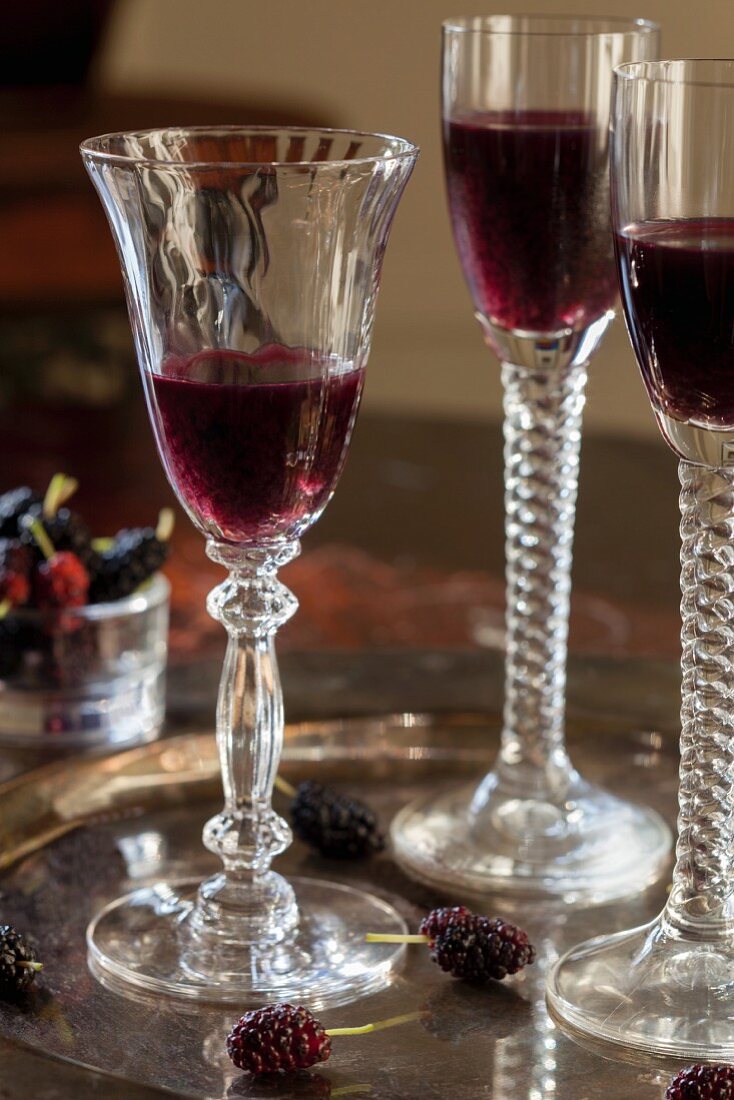 Mulberry liqueur in three stemmed glasses on a tray