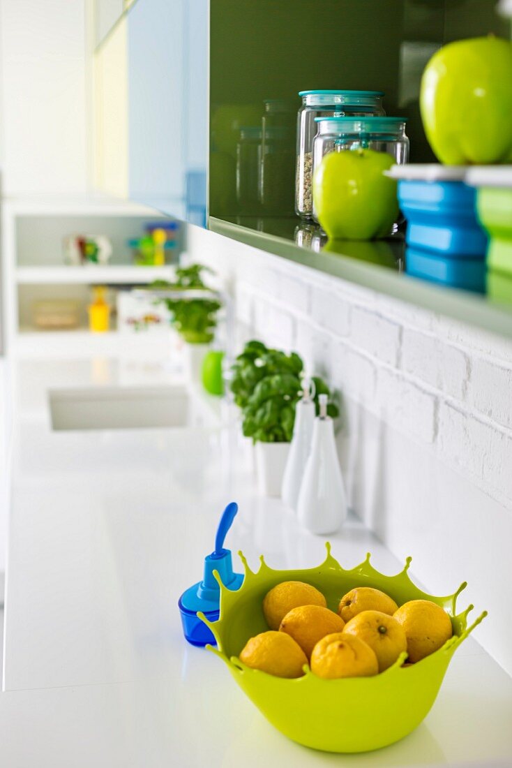 Shades of blue and green in wall cabinet and on sink unit of white kitchen counter