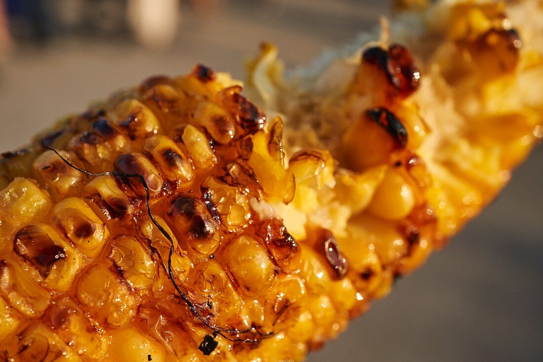 A grilled corn cob (with a bite taken out) at a market in New York