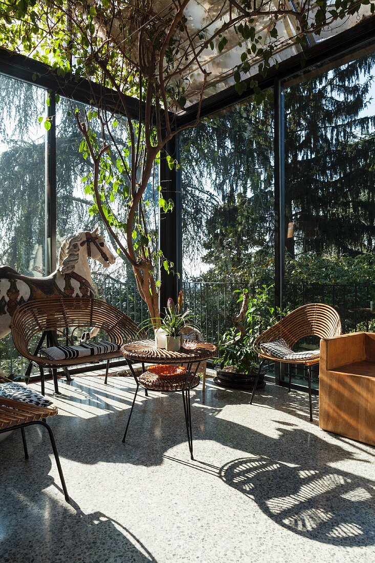 Wicker bench and chairs around matching retro table in light-flooded conservatory