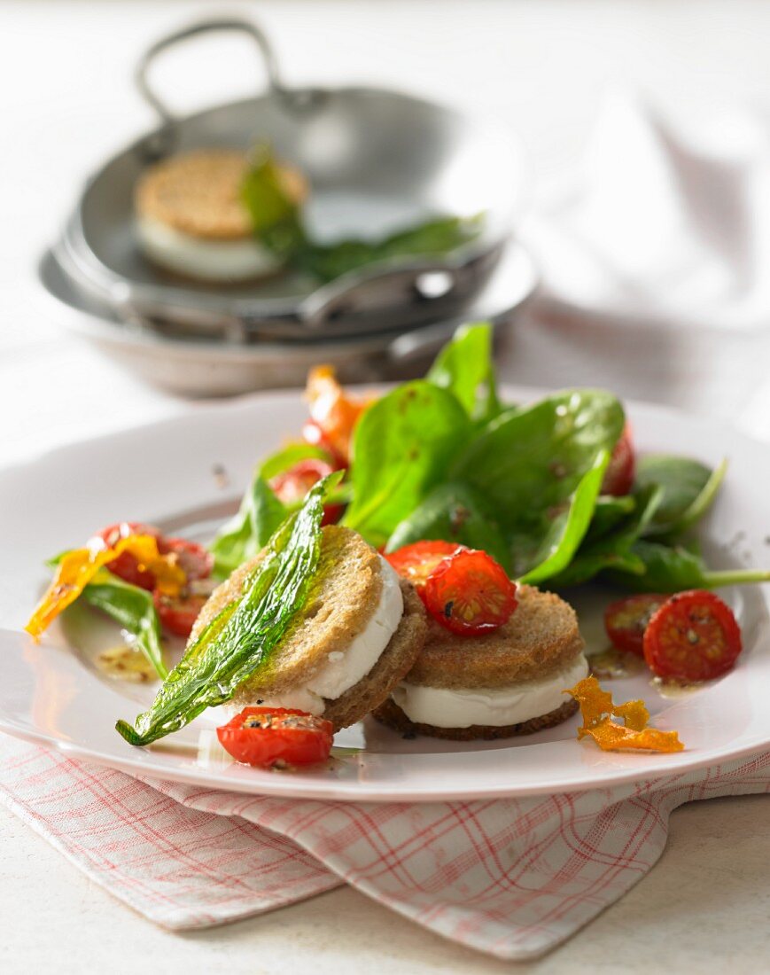 Spinach salad with cherry tomatoes, goats cheese and fried wild garlic