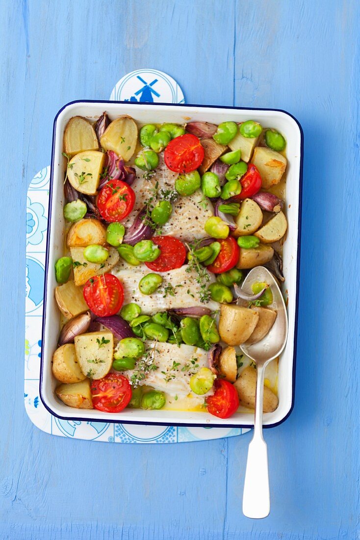 Baked cod with potatoes, broad beans, garlic, onions and tomatoes