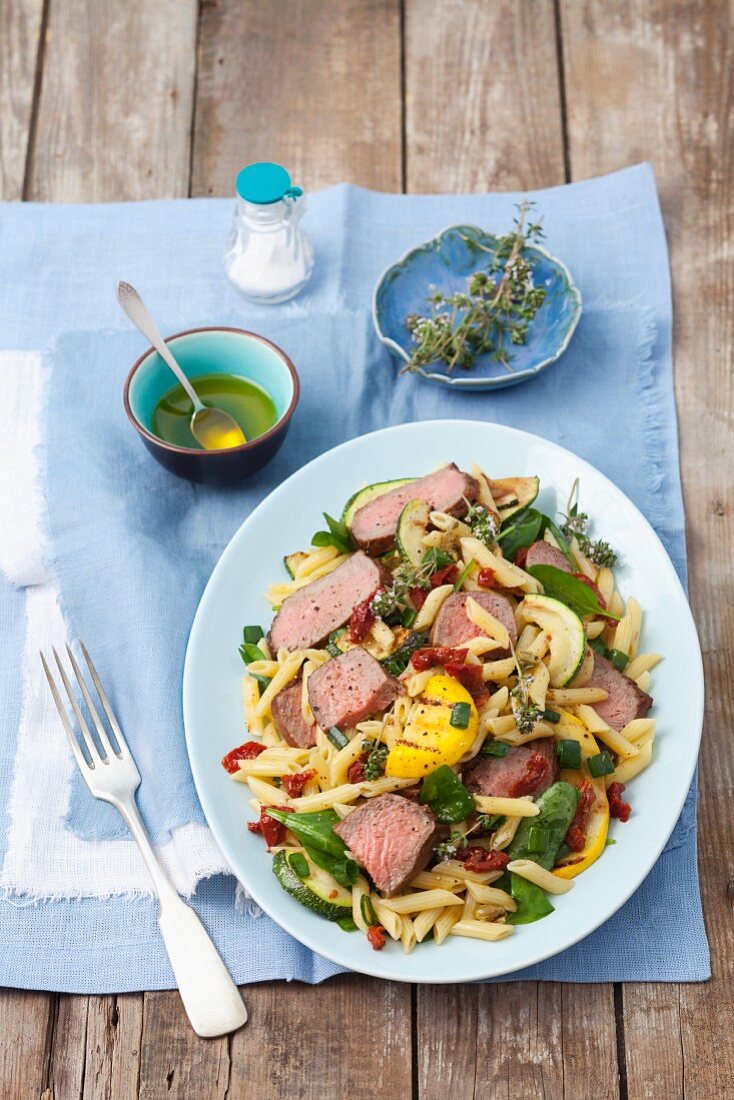 Penne pasta salad with roast beef, courgettes, dried tomatoes and spinach