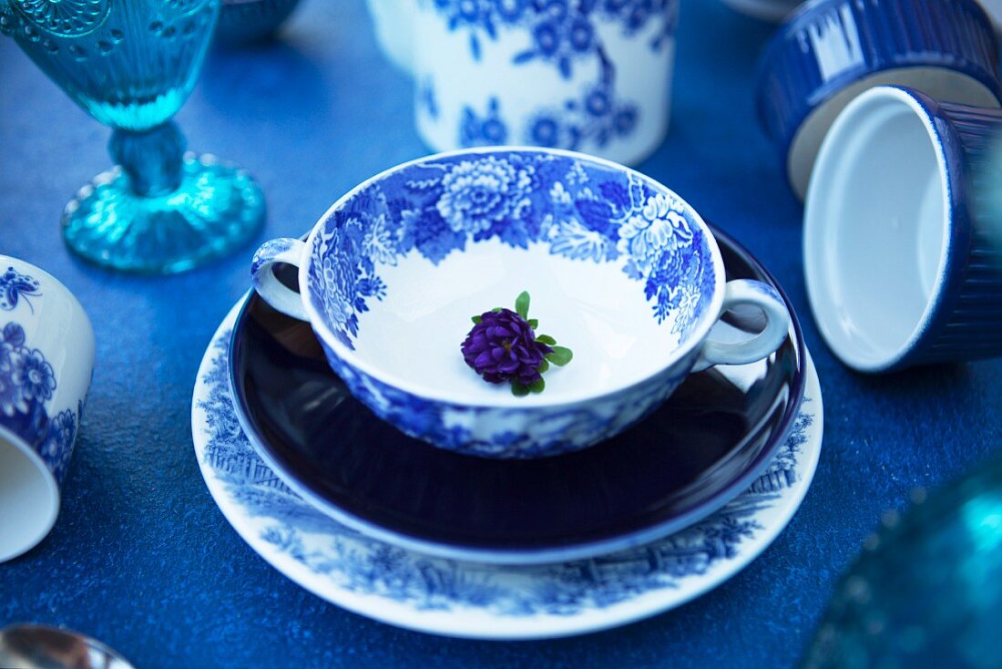 Blue plates, a soup cup, glasses and baking tins on a blue table
