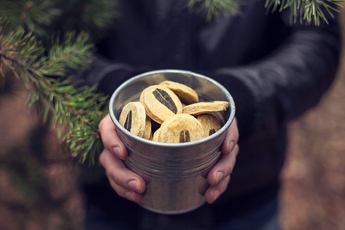 A man holding a metal bucket of green tea cookies