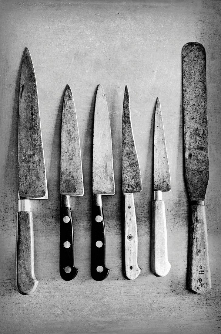 Old kitchen knives on a metal surface