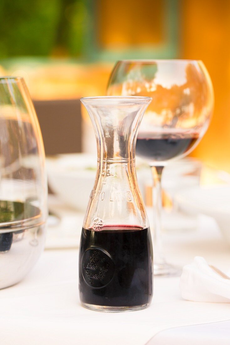 Rotwein in Glas und Karaffe auf gedecktem Tisch