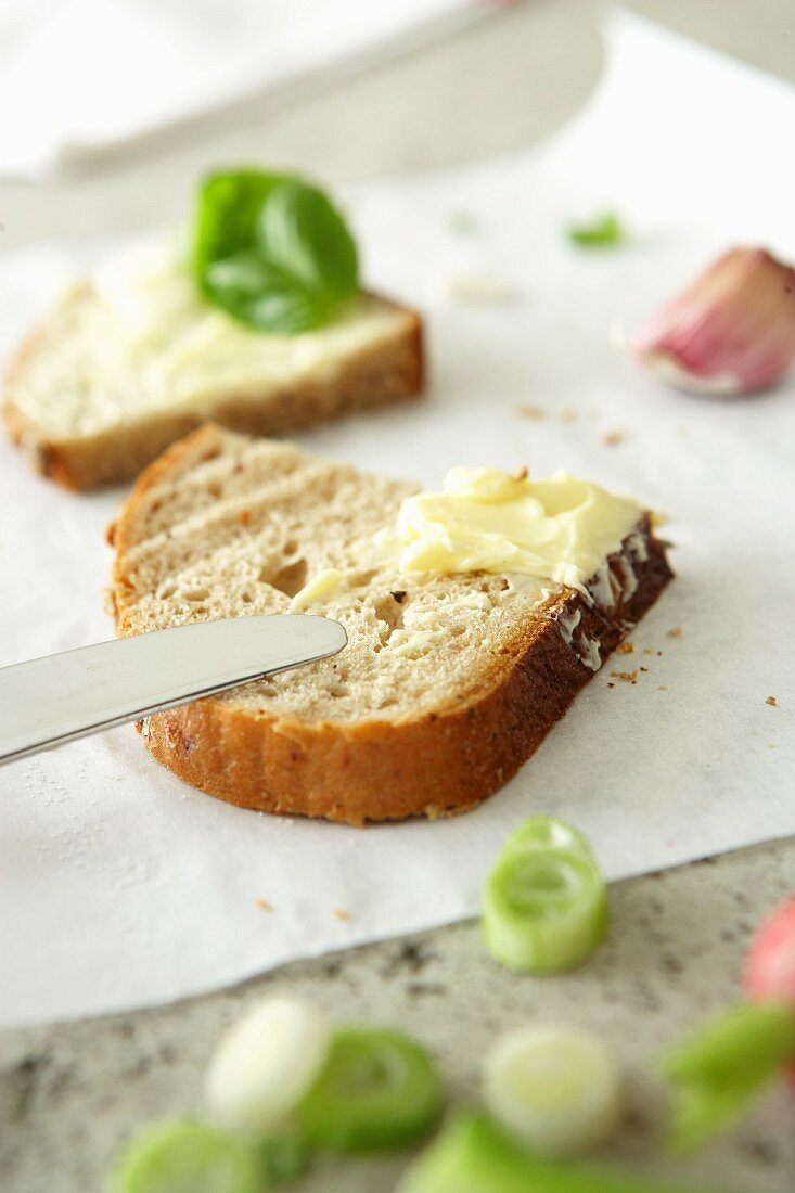 A slice of bread being spread with butter