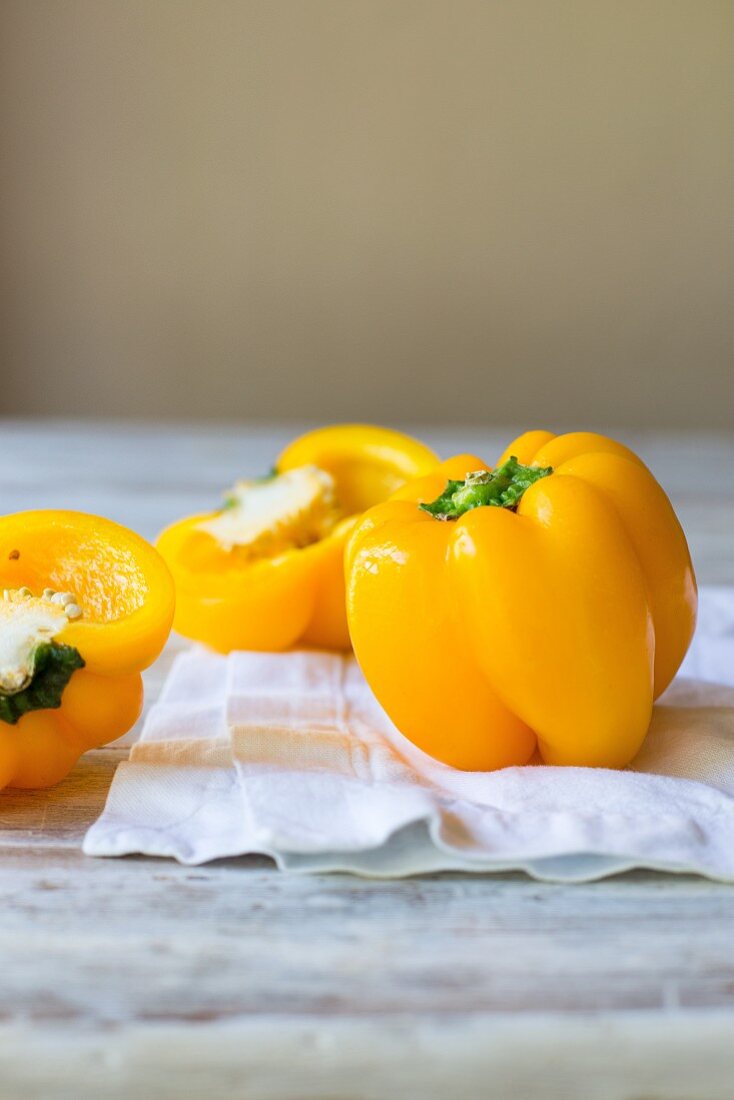 Fresh whole and halved yellow peppers with water droplets