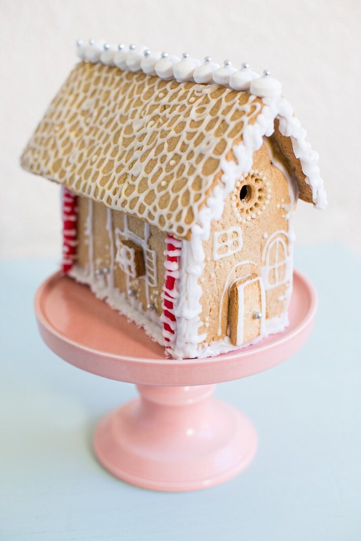 A gingerbread house on a pastel pink cake stand