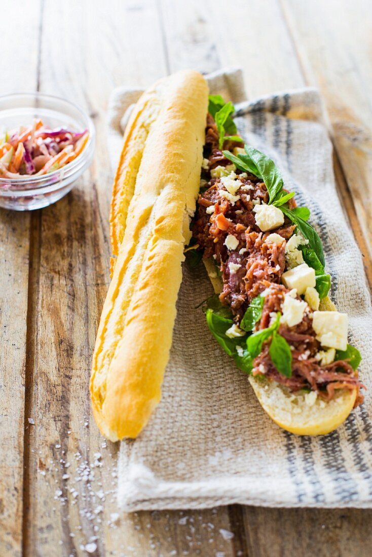 A pulled pork baguette with mustard sauce, basil and feta cheese