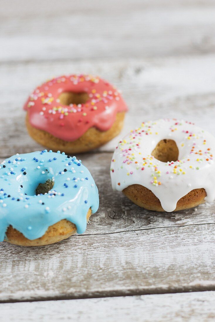 Mini-Doughnuts mit rosa, blauem und weißem Zuckerguss und bunten Zuckerperlen