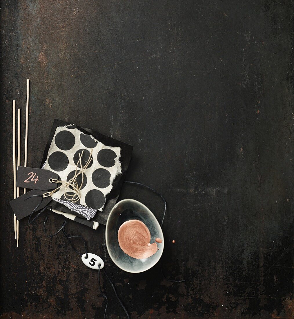 Black and white mood board with chopsticks, labels, paper and bowl of paint