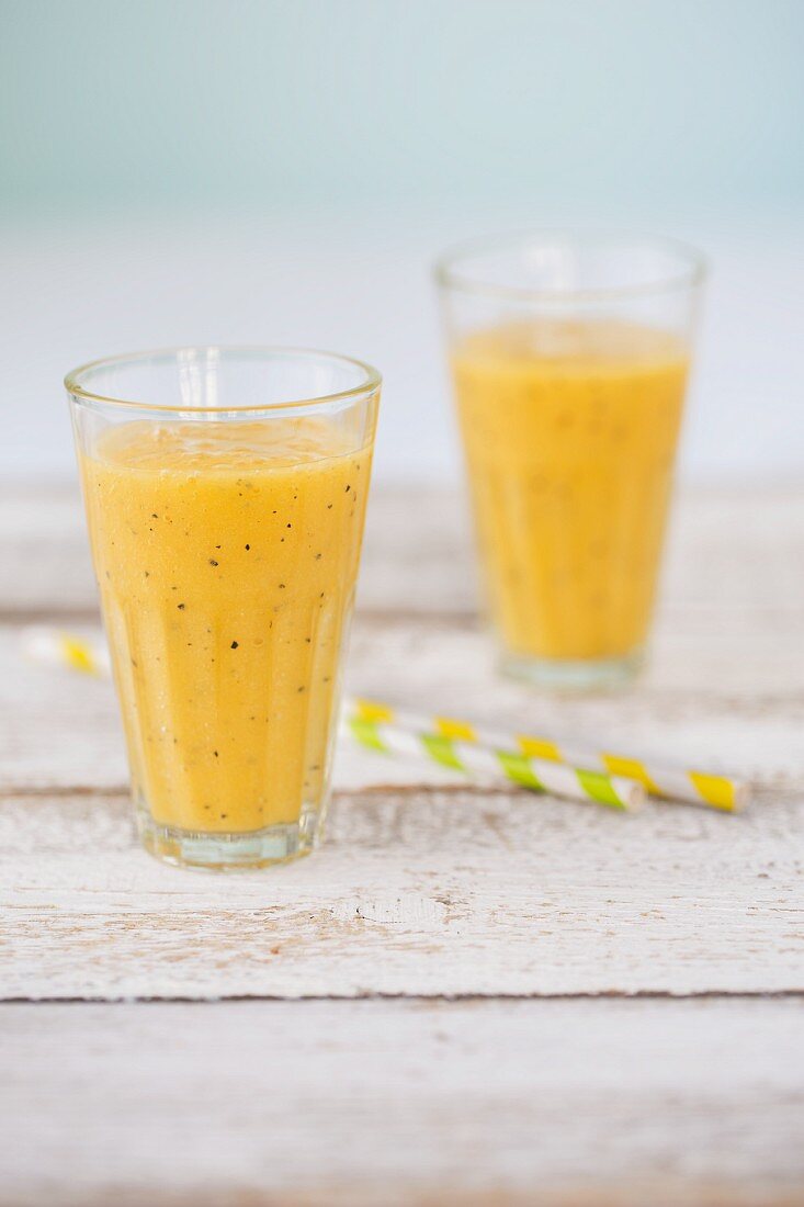 Two smoothies (mango and passion fruit, pineapple and grapefruit) in glasses
