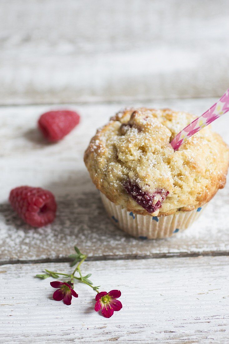 Himbeermuffin mit frischen Himbeeren und kleinen pinken Blüten