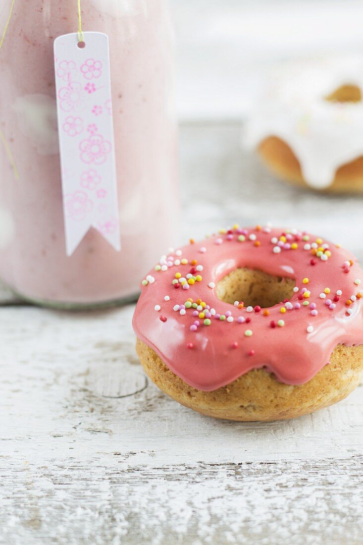 A bottle of strawberry milkshake with yoghurt spots and mini iced doughnuts