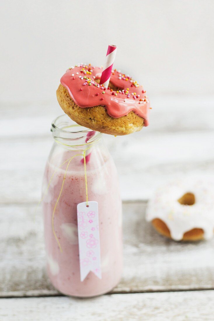 Erdbeermilch mit Joghurtpunkten in Flasche und Mini-Doughnuts mit Zuckerguss