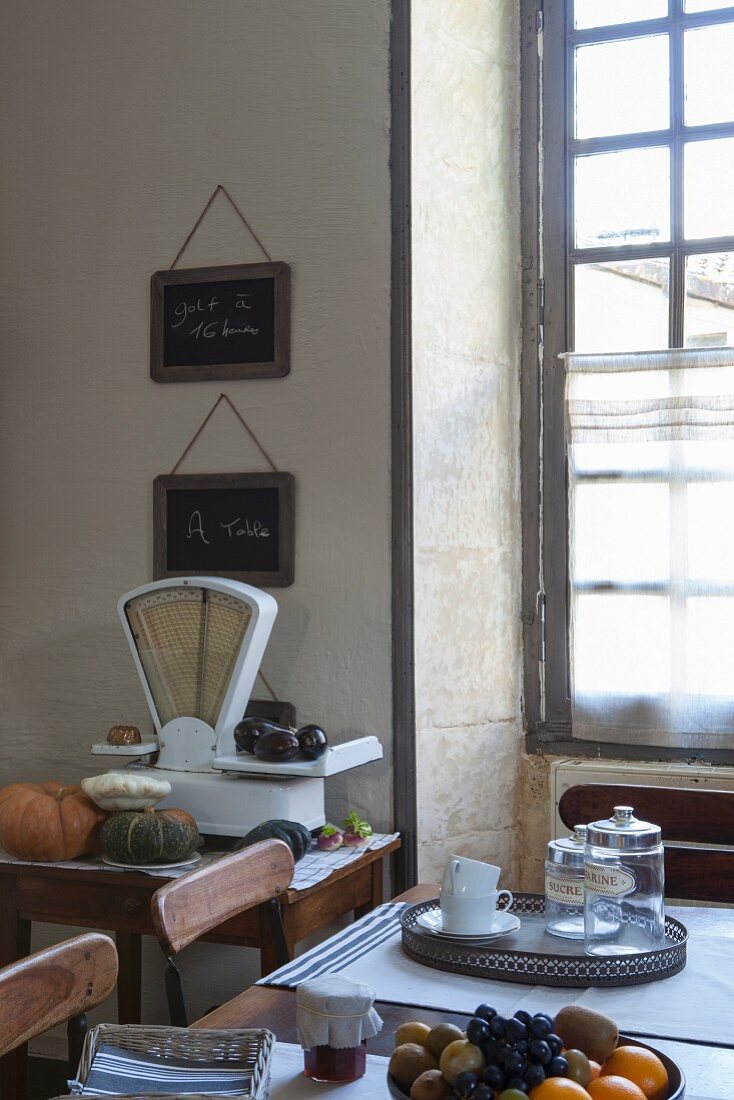 Antique scales, lattice window and fruit bowl on wooden table in Mediterranean kitchen