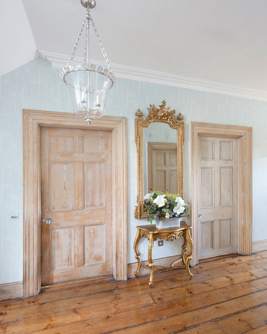 Antique furniture, two panelled doors and old wooden floor in foyer