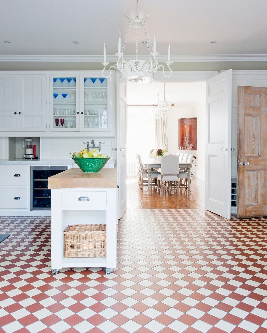 Geräumige Küche mit Kücheninsel und rot-weißem Schachbrettboden, Blick ins Esszimmer