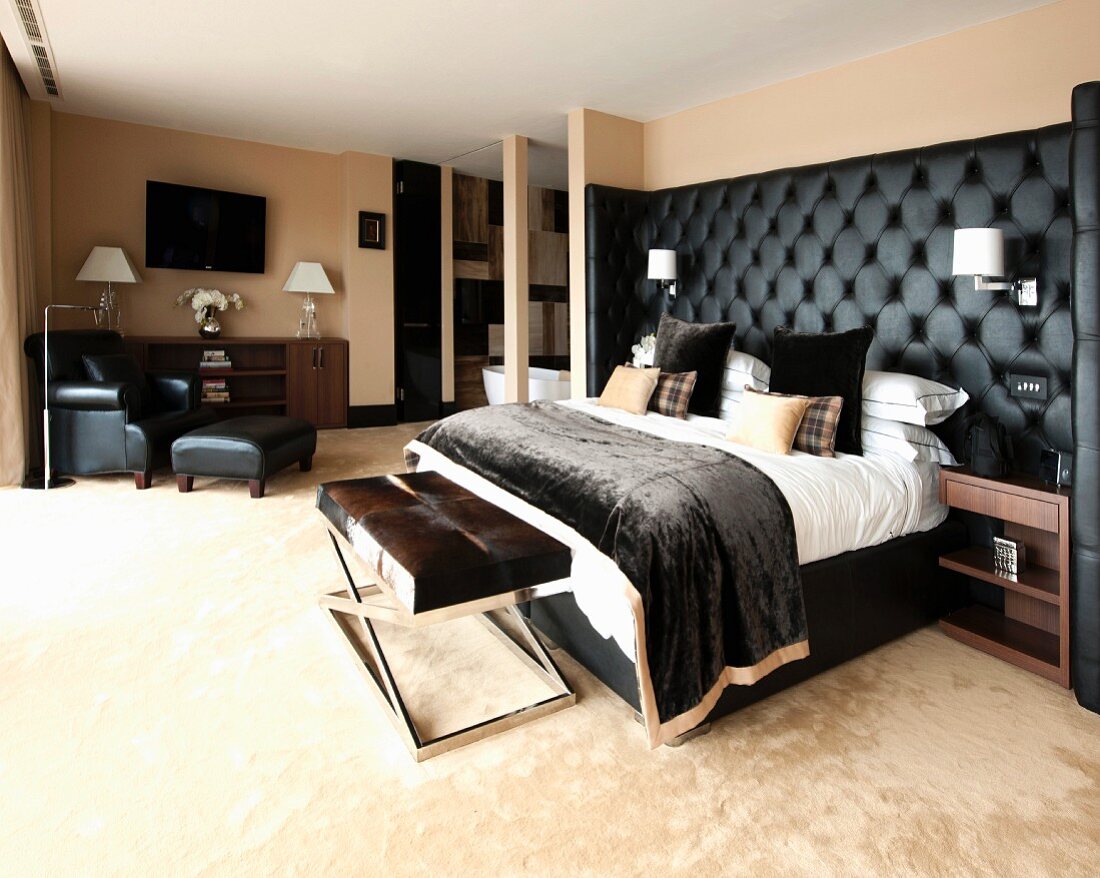 Maskulines Schlafzimmer mit schwarz gepolstertem Betthaupt, Bettbank und Lesesessel