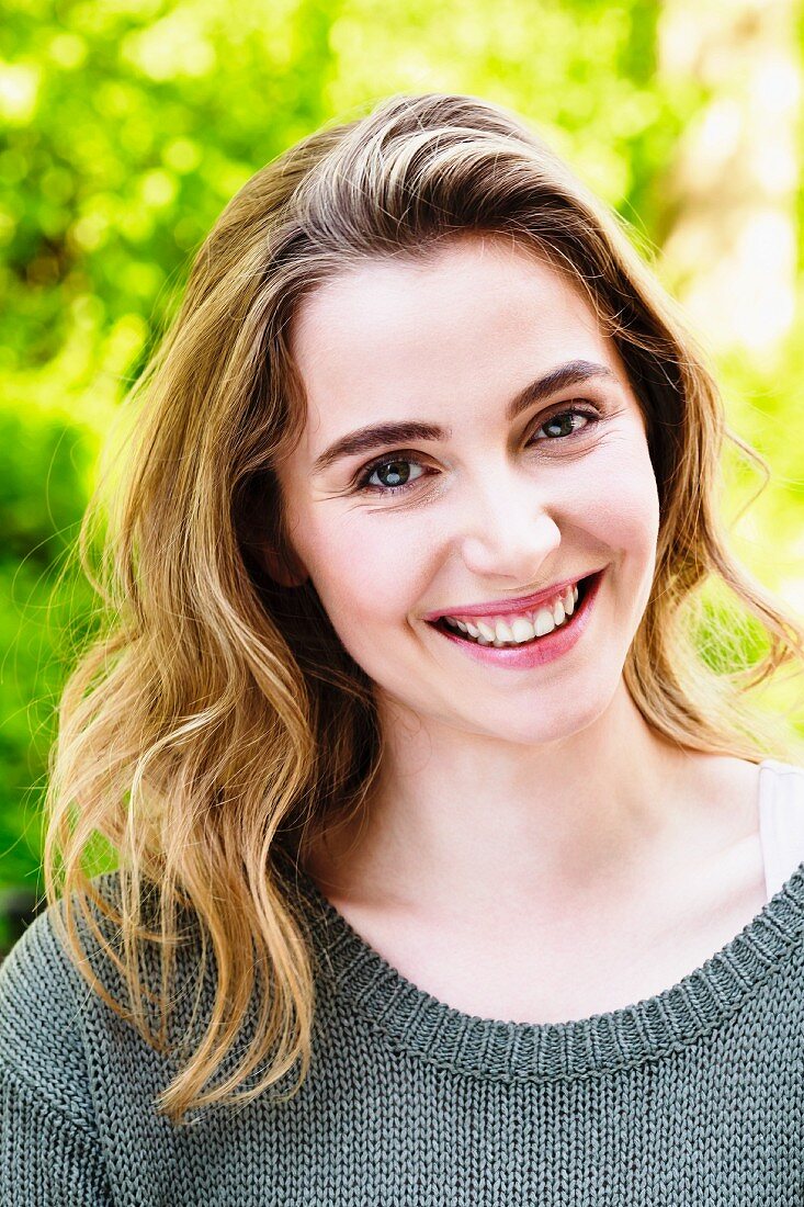 A portrait of a dark-blonde woman wearing a grey knitted jumper