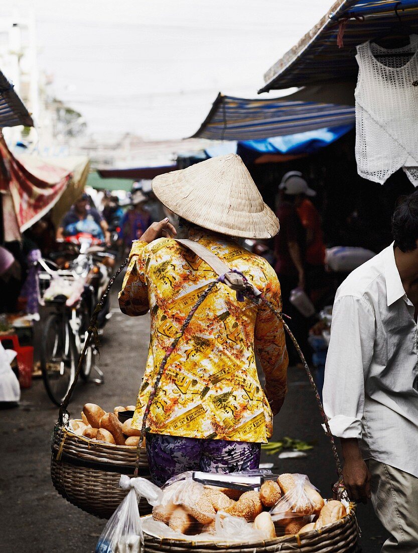 Verkäuferin mit Brötchen auf dem Markt, Vietnam