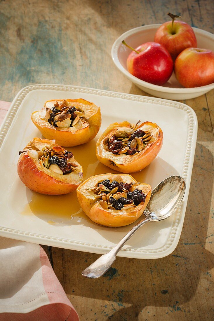 Baked apple halves filled with dried fruits and seeds on a cider sauce