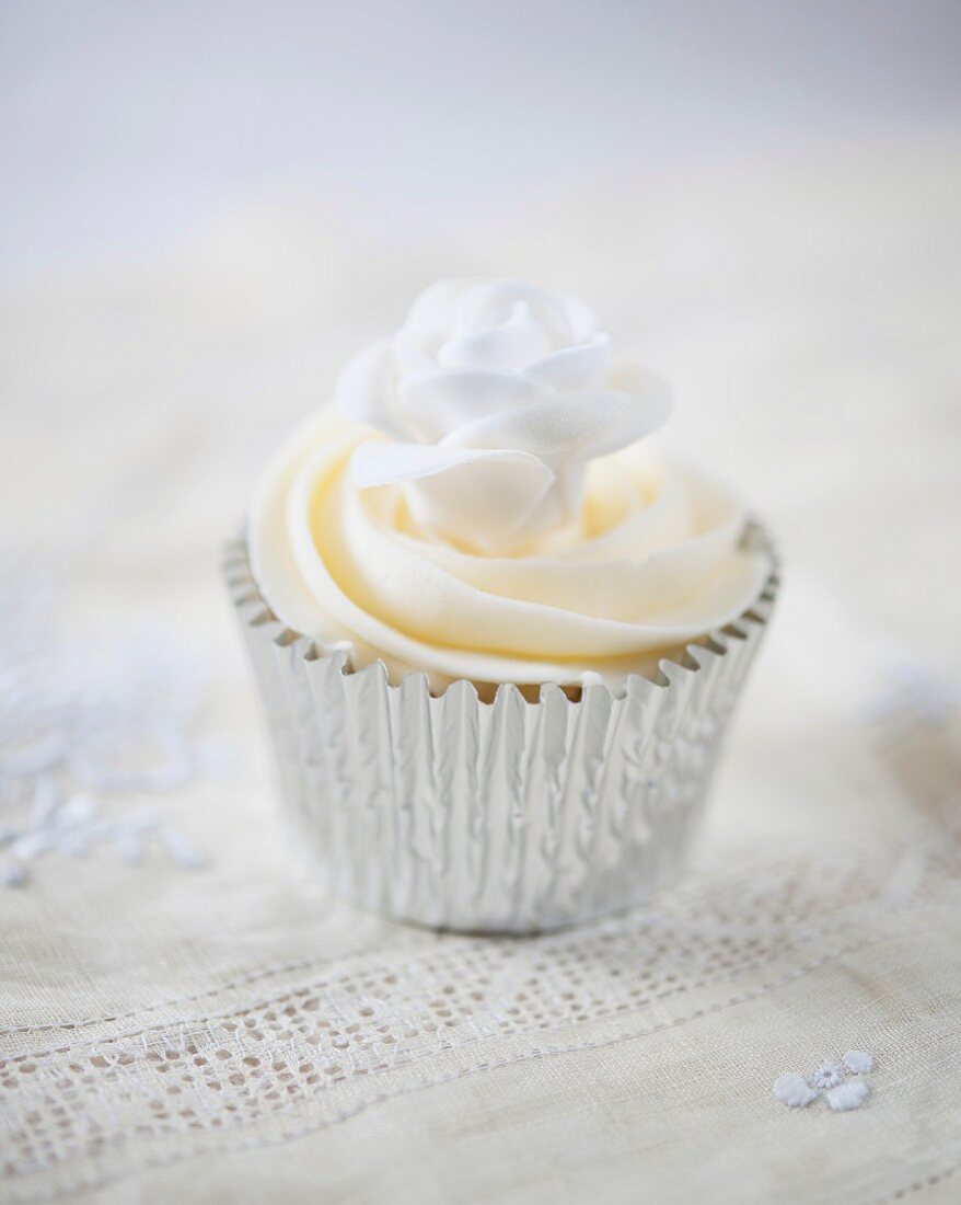 A cupcake decorated with a white sugar rose